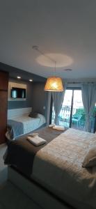 a bedroom with two beds and a light hanging from the ceiling at MODERNO MONOAMBIENTE- LA CALLEJA APART in Olavarría