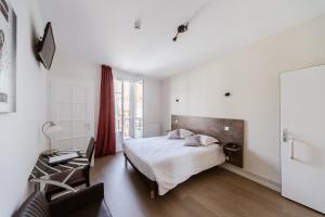 a white bedroom with a bed and a chair at LOGIS HOTEL - Le Petit Bellon in Senlis