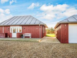 a red shed with a bench on a patio at 8 person holiday home in Tarm in Tarm
