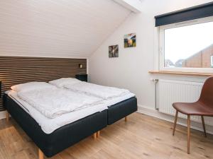 a bed in a room with a window and a chair at 4 star holiday home in Rømø-By Traum in Sønderby
