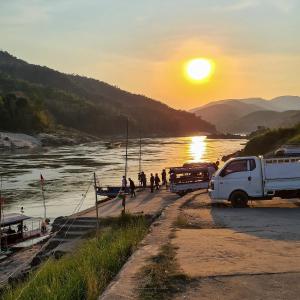 een vrachtwagen geparkeerd naast een rivier bij zonsondergang bij Mekong backpackers 2 in Pakbeng +59 foto's