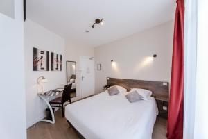 Un dormitorio con una cama blanca y un escritorio. en LOGIS HOTEL - Le Petit Bellon, en Senlis