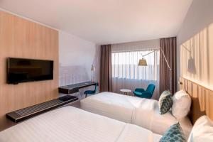 a hotel room with two beds and a flat screen tv at Courtyard by Marriott Brno in Brno