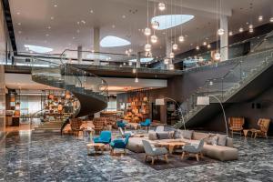 ブルノにあるコートヤード バイ マリオット ブルノの階段、椅子、テーブルのあるロビー