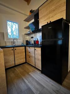 a kitchen with a black refrigerator and wooden cabinets at The cabins Project Σπίτια στο δάσος in Konstandiniá