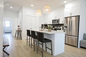 エドモントンにあるChic Modern Home,King Bed,Fireplace,Disneyの白いキャビネット付きのキッチン、バーチェア付きのキッチンアイランド
