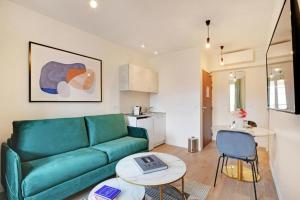 a living room with a green couch and a table at La lumière de Paris in Levallois-Perret