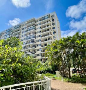 a large apartment building with trees in front of it at Barra Family Resort com piscina e spa, 2 quartos in Rio de Janeiro