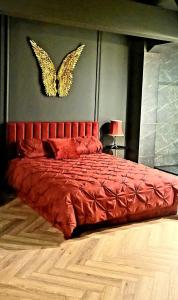 a bedroom with a red bed with a butterfly sign on the wall at Apartament Plac Zabaw in Łódź