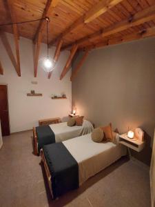 Dos camas en una habitación con techos de madera. en Casa Serena Mar, en Balneario El Condor