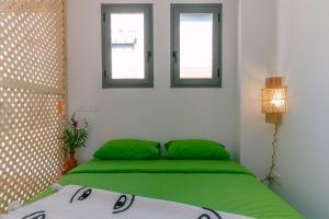 a bedroom with a green bed with two windows at Appartement Taghazout in Taghazout