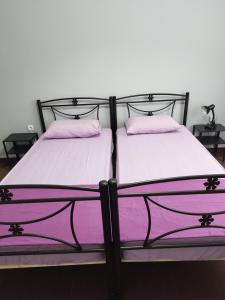 two beds in a room with purple sheets and pillows at Rental room pilika4 in Athens