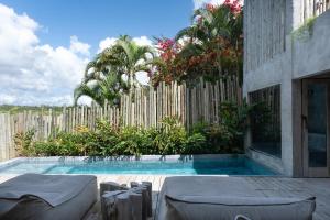 a swimming pool in front of a wooden fence at Pousada Zinga Vila de Caraíva in Caraíva