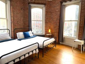 een slaapkamer met twee bedden en een bakstenen muur bij Nest aparthotel with kitchenette in New York