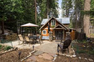 una cabaña en el bosque con mesa y sillas en Cozy Yosemite Cabin with Hot Tub in the Pines, en Fish Camp
