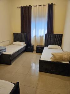 two beds sitting in a room with a window at Hostel Faye in Abu Dhabi