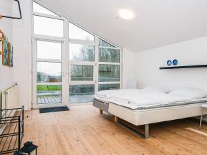 a white room with a bed and large windows at 16 person holiday home in Højer in Højer +49 photos