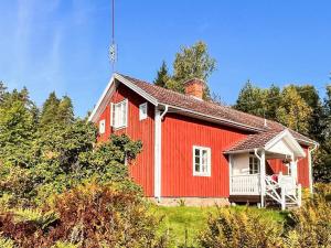 a red house with a white porch next to trees at 4 star holiday home in åMMEBERG in Åmmeberg