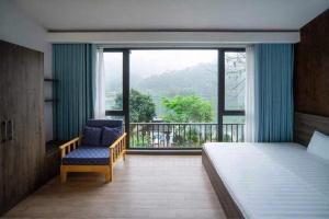 a bedroom with a bed and a chair and a window at Lavita villa Resort in Sóc Sơn