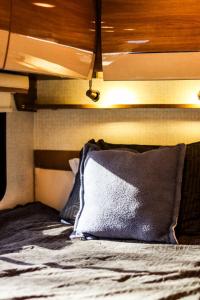 a bed with a gray pillow on top of it at Navi- HUGE yard- MEGA playset- CUTE RV in Willmar