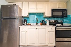 a kitchen with white cabinets and a stainless steel refrigerator at Pet Friendly Modern Oceanfront Suite in Myrtle Beach