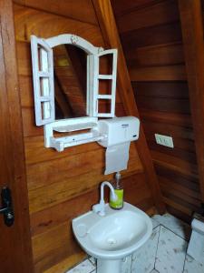 Un baño con un lavabo blanco y un espejo. en Recanto sol maior - Chalé Jasmin, en Sapucaí-Mirim