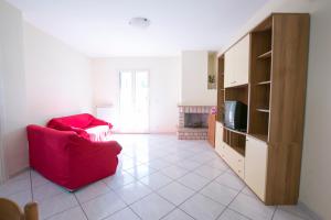 ein Wohnzimmer mit einem roten Sofa und einem TV in der Unterkunft Orchidea Pineto Vacanza in Pineto
