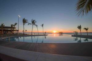 een zwembad met palmbomen en de oceaan bij zonsondergang bij Air-conditioned Cooee Bay Beach House with Wi-Fi in Yeppoon
