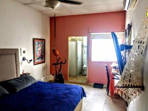 a bedroom with a blue bed and a red wall at Depa Terraza San Isidro in Torreón