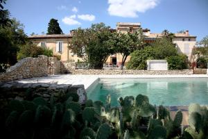 a swimming pool in front of a house with cactus at La Rougeanne in Moussoulens