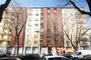un grand bâtiment avec des voitures garées devant dans l'établissement Lomellina 13, à Milan