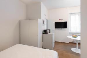 Cette chambre blanche dispose d'un réfrigérateur et d'une table. dans l'établissement Lomellina 13, à Milan