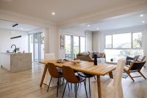 a dining room and living room with a wooden table and chairs at Luxurious Waterfront Retreat in Oatley in Oatley