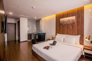 a bedroom with a white bed with a wooden wall at Gold Central Hotel by Haviland in Da Nang
