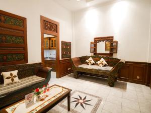 ein Wohnzimmer mit 2 Sofas und einem Spiegel in der Unterkunft Rumah Pesik Art & Heritage Hotel in Gondowulung