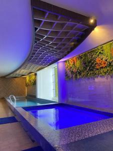a large swimming pool with blue lighting in a building at OPA Hotel Palembang in Sukarami