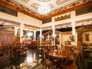 ein Restaurant mit Holztischen und -stühlen sowie einem Kronleuchter in der Unterkunft Rumah Pesik Art & Heritage Hotel in Gondowulung