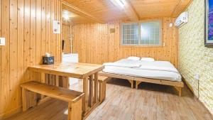 a wooden room with a bed and a table at Jeju CountryFarmpension in Seogwipo