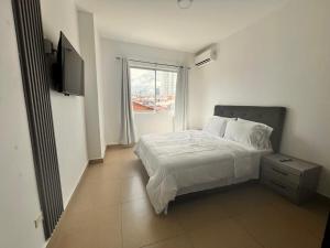 a white bedroom with a bed and a window at Family Apartment in San Francisco in Panama City