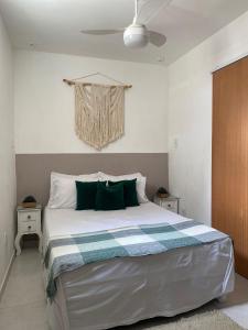 une chambre avec un grand lit blanc avec des oreillers verts dans l'établissement Loft Ymará Arraial, à Arraial do Cabo