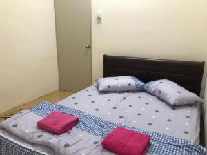 a bed with two pillows and two pink towels on it at Fauziyah melaka in Air Molek