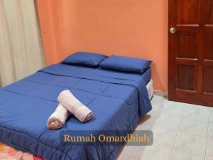 a bed with a blue comforter and a towel on it at Rumah Omardhiah in Kuala Terengganu