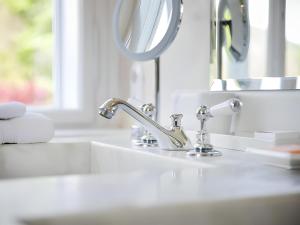 a bathroom sink with a faucet and a mirror at Garden Cottage Villa Lichtenstein - Your Austrian Home in Altaussee