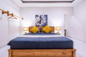 a bedroom with a blue bed with yellow pillows at Villa Gaia Canggu in Canggu