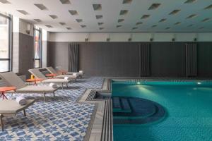 a pool in a room with chairs and a table at Moselle Armenia Wellness & Medical SPA Jermuk in Jermuk