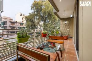 einen Balkon mit Bänken und einem Glastisch in der Unterkunft StayVista at Sundale Apartment with Heater & WiFi in Varanasi