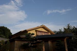 ein Haus mit Dach und Zaun in der Unterkunft TAKITEI Riverside Onsen ーA Hidden Ryokan in Kanazawaー in Kanazawa