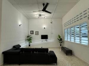 a living room with a black couch and a tv at Yipstay Gopeng HomeTown in Gopeng