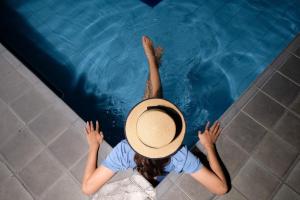 a woman in a hat in a swimming pool at Kusuma Sahid Prince Hotel Solo in Solo