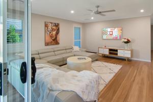 Una sala de estar con un sofá y un televisor. en Thane Retreat - Cosy Ambience, Modern Entertaining, en Wagga Wagga